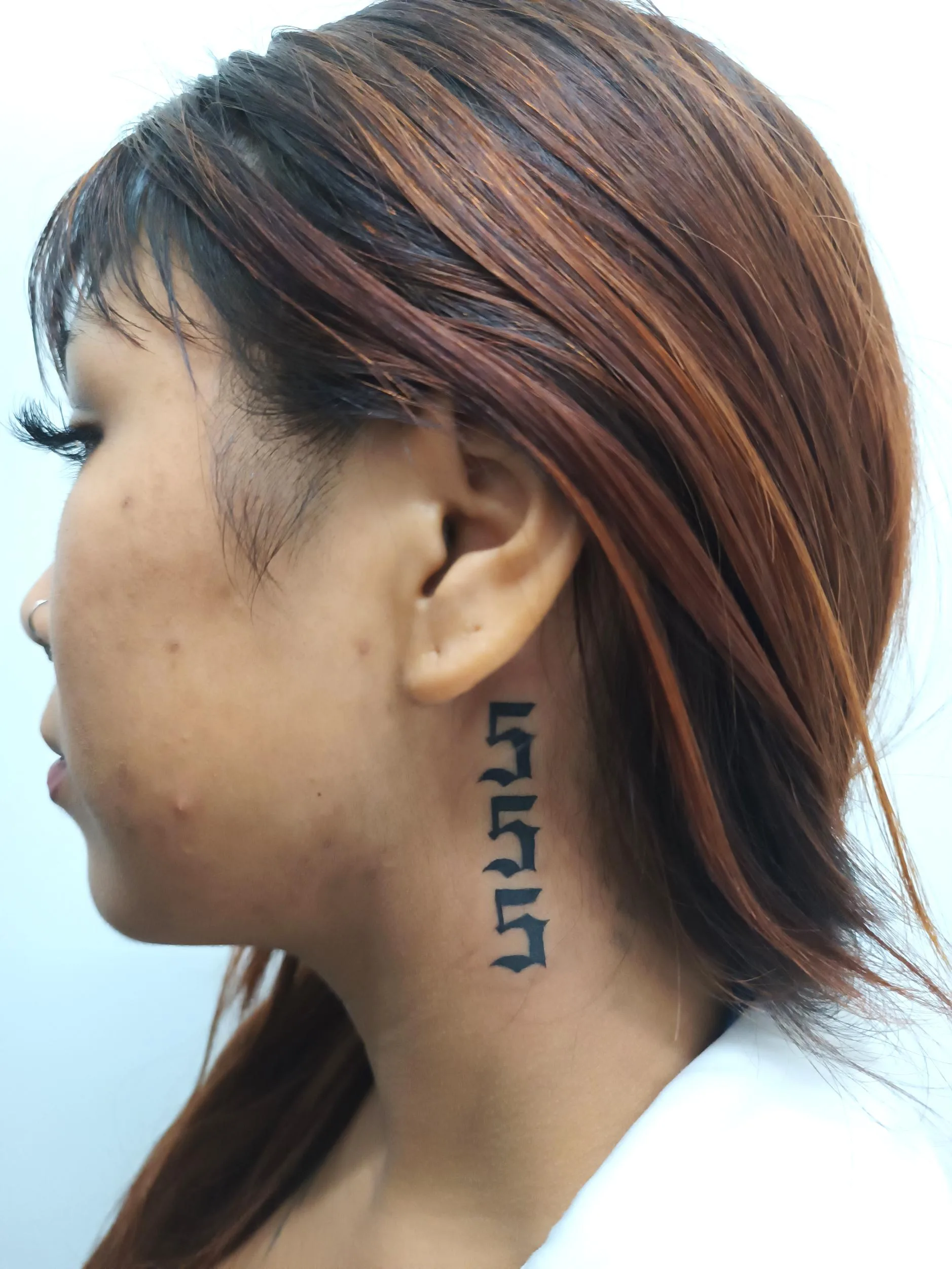 Tatuaje en el cuello con números "555" en tipografía gótica negra vertical, sencillo y llamativo.