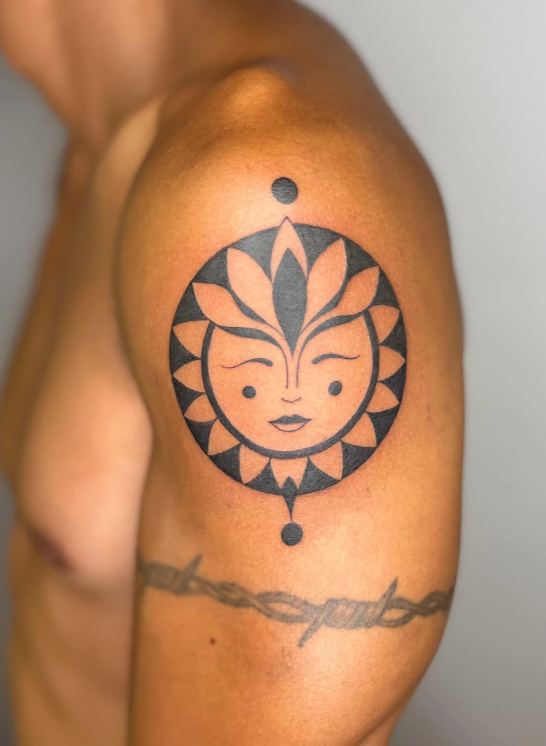 Sol con rostro humano en negro, pétalos geométricos y puntos decorativos, diseño simbólico y moderno.