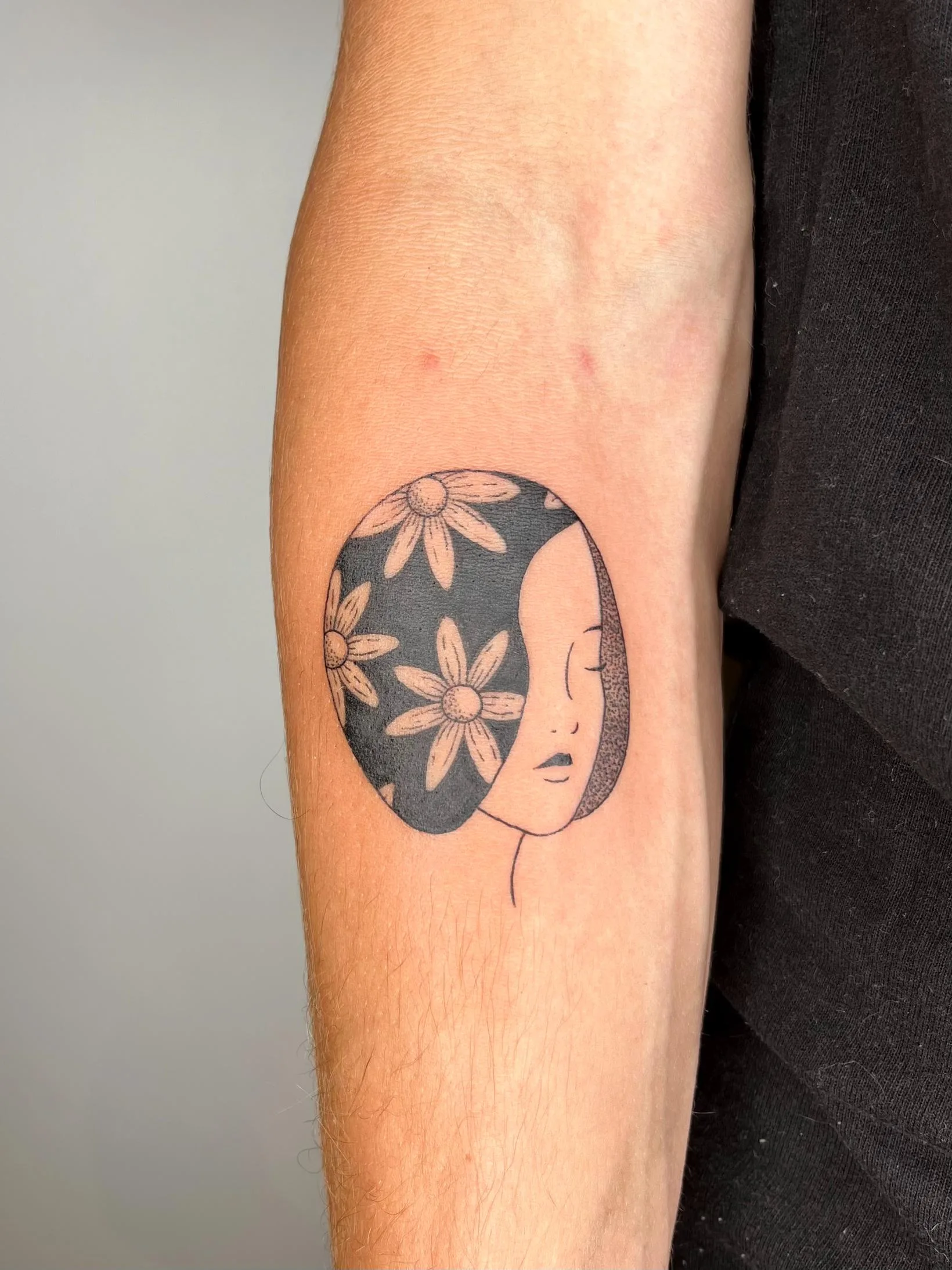 Tatuaje de la cara de una mujer de perfil con cabello negro decorado con margaritas blancas, artístico y delicado.