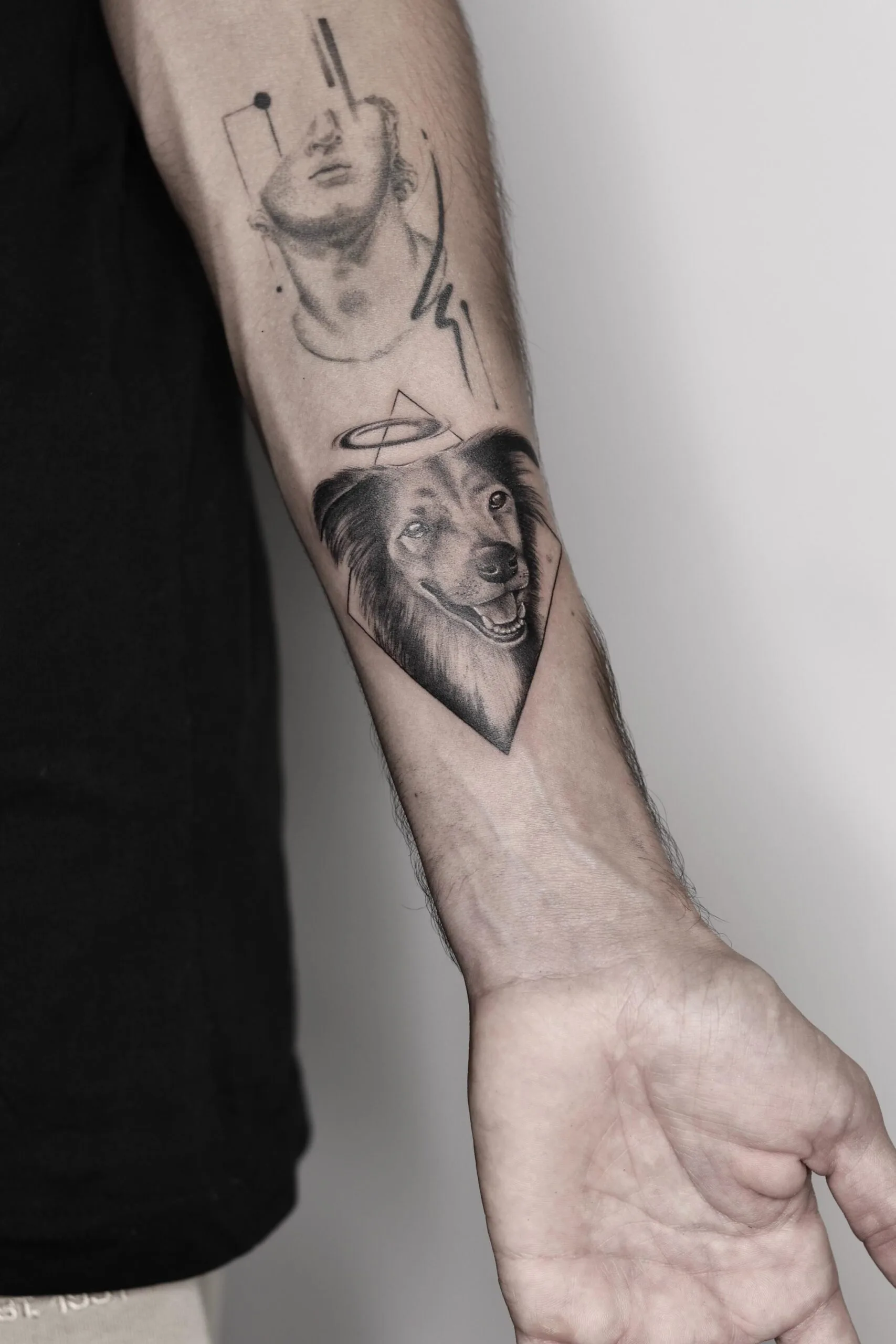 Tatuaje en el antebrazo de un perro estilo microrealismo con halo, junto a un retrato abstracto en líneas negras.