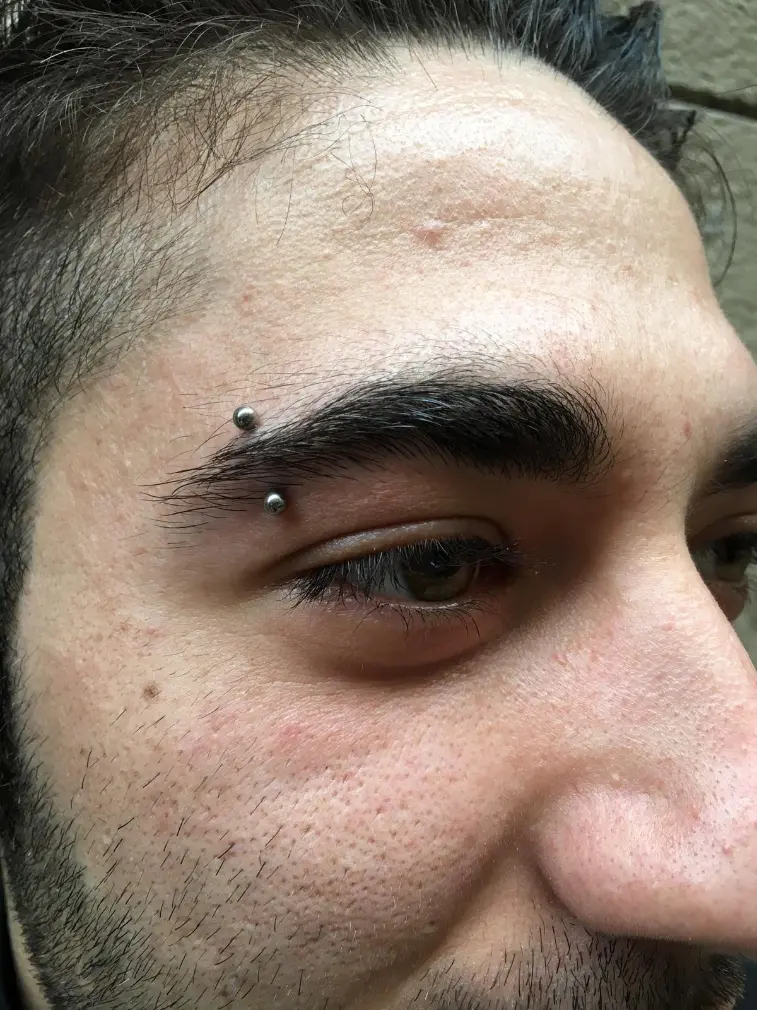 Hombre con un piercing en la ceja hecho en sun tattoo barcelona.